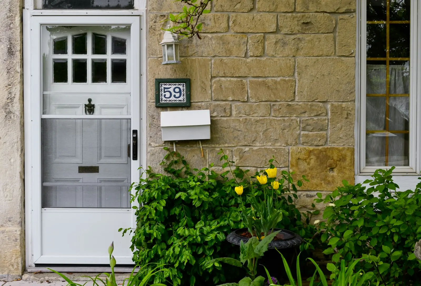 A white front door beside a stone wall