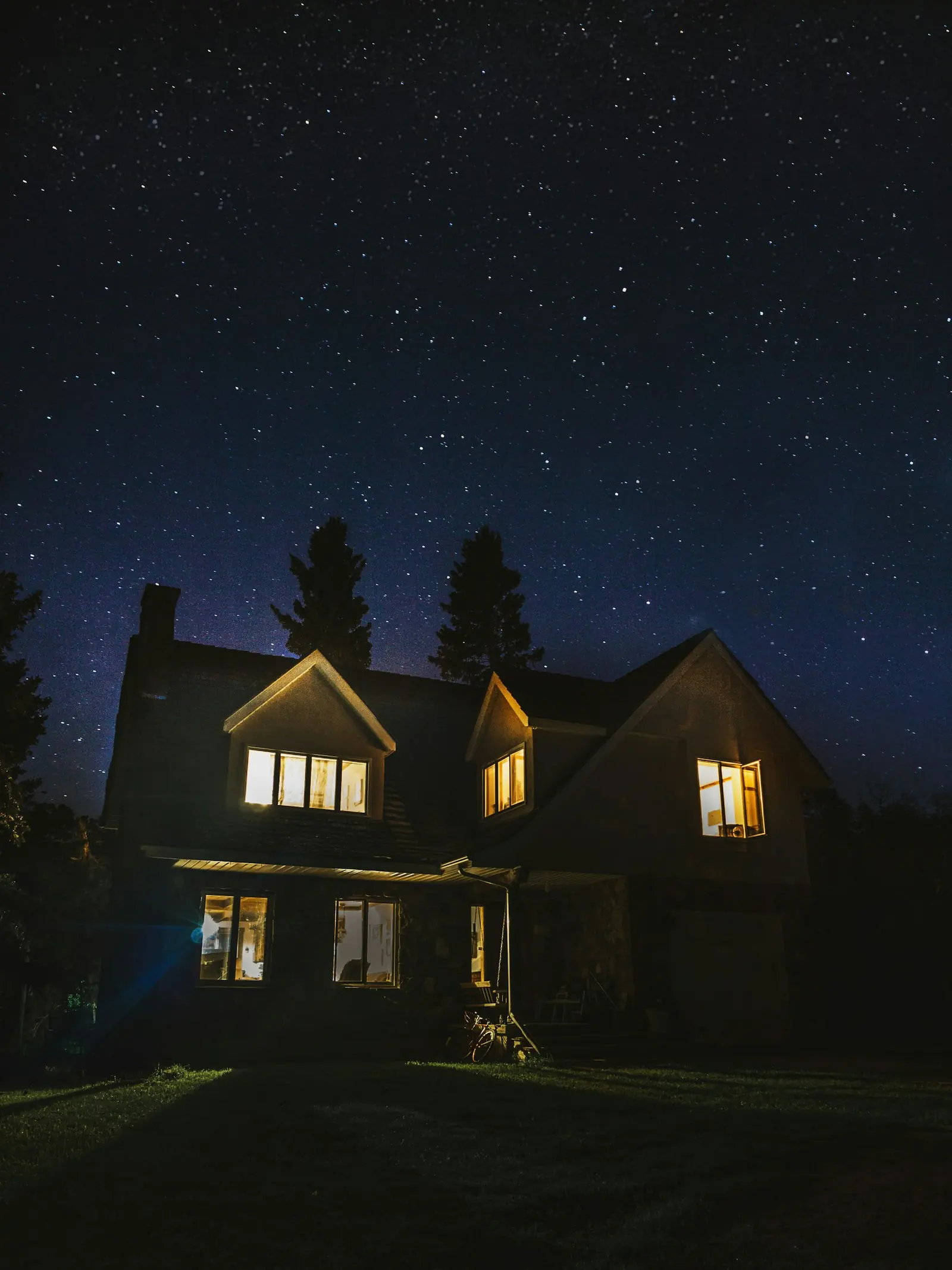 A house under a sky full of stars, its windows lit