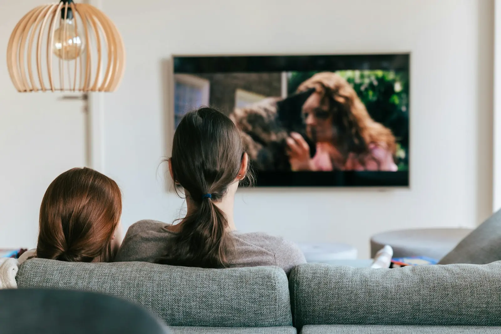Two people on a sofa watching a film on a wall-mounted TV